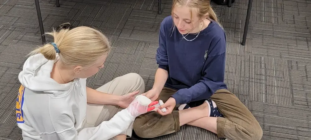 Two people paired up to learn how to properly bandage wounds in Evolution's CSA first aid and cpr course